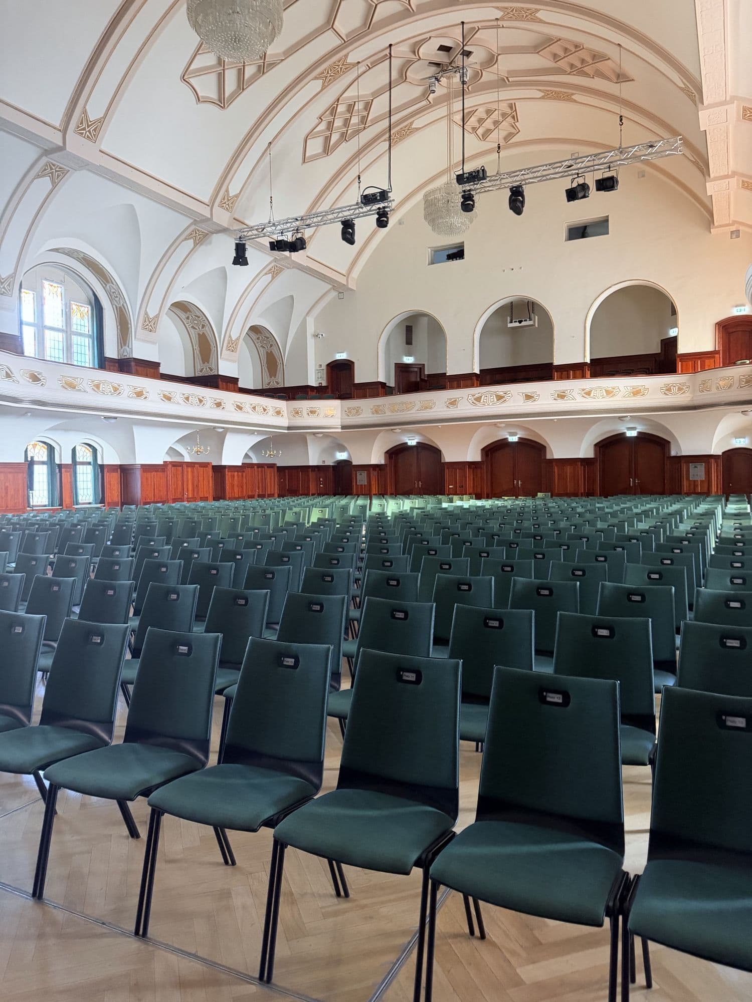 Stuhlreihen im großen Saal des Volkshauses unter der verzierten Decke